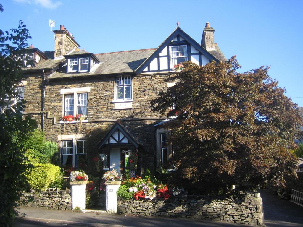 The stone exterior and flower-filled garden of Denehurst Guest House in Windermere